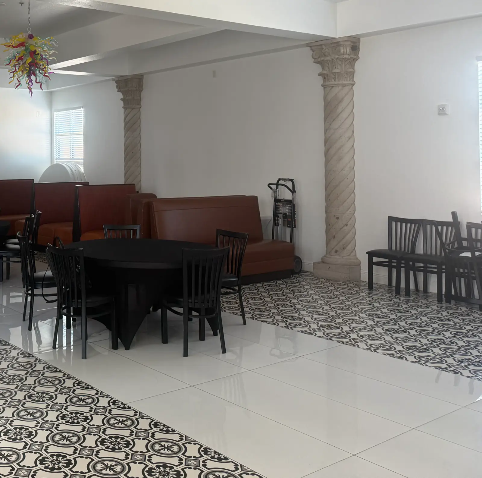 El salón de eventos de Tink-A-Tako #12, 7507 Potranco Rd: piso de mosaico blanco y negro, columnas salomónicas de cantera, gabinetes de piel y una mesa redonda con sillas